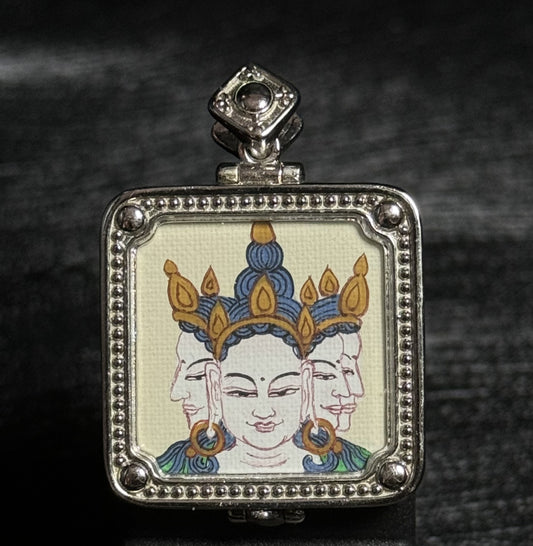 Front view of a hand-painted Vairocana Buddha miniature thangka pendant showing the three-faced Buddha depiction painted with mineral pigments inside a detailed 925 silver plated frame.