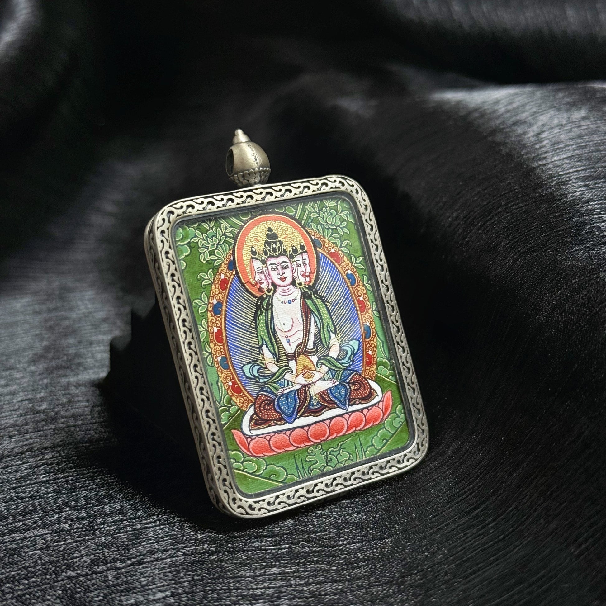Detailed view of Vairocana Buddha mini thangka pendant painted with natural mineral pigments in the Rebgong thangka tradition.