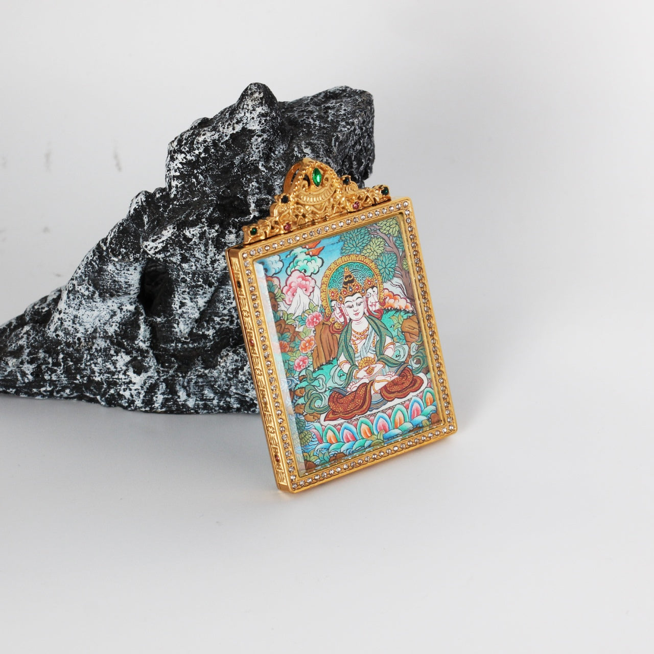 Angled view highlighting the crystal-set frame and side thickness of a gold-tone double-sided titanium steel mini thangka pendant with Vairocana Buddha painting, Nepal hand-painted artwork