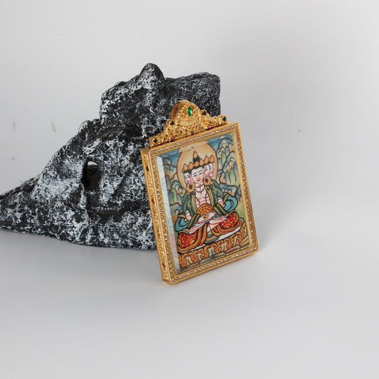Angled view of the Vairocana Buddha mini thangka pendant highlighting the crystal-set border, gold-tone case depth, and ornate crown top with green and multicolor stones, with the hand-painted artwork visible through the front window.
