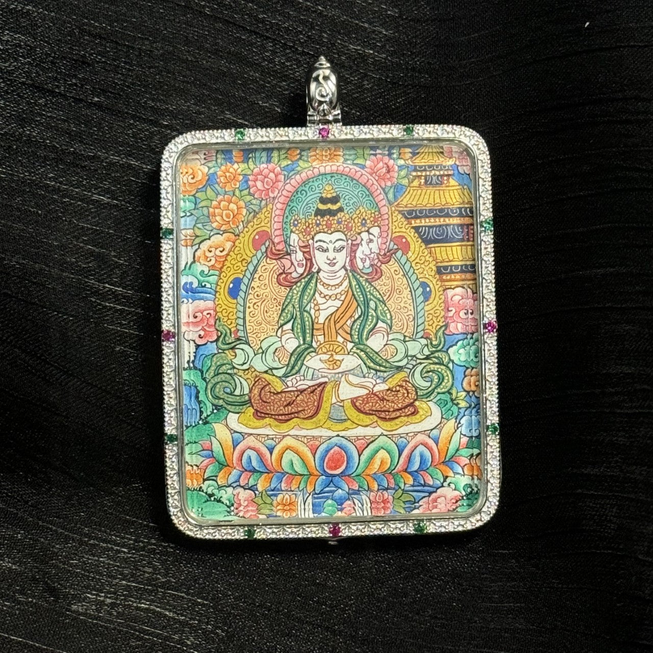 Detailed close-up of the Vairocana Buddha mini thangka pendant highlighting mineral pigment painting, lotus throne, decorative halo, and intricate Tibetan floral patterns inside a square silver pendant setting.