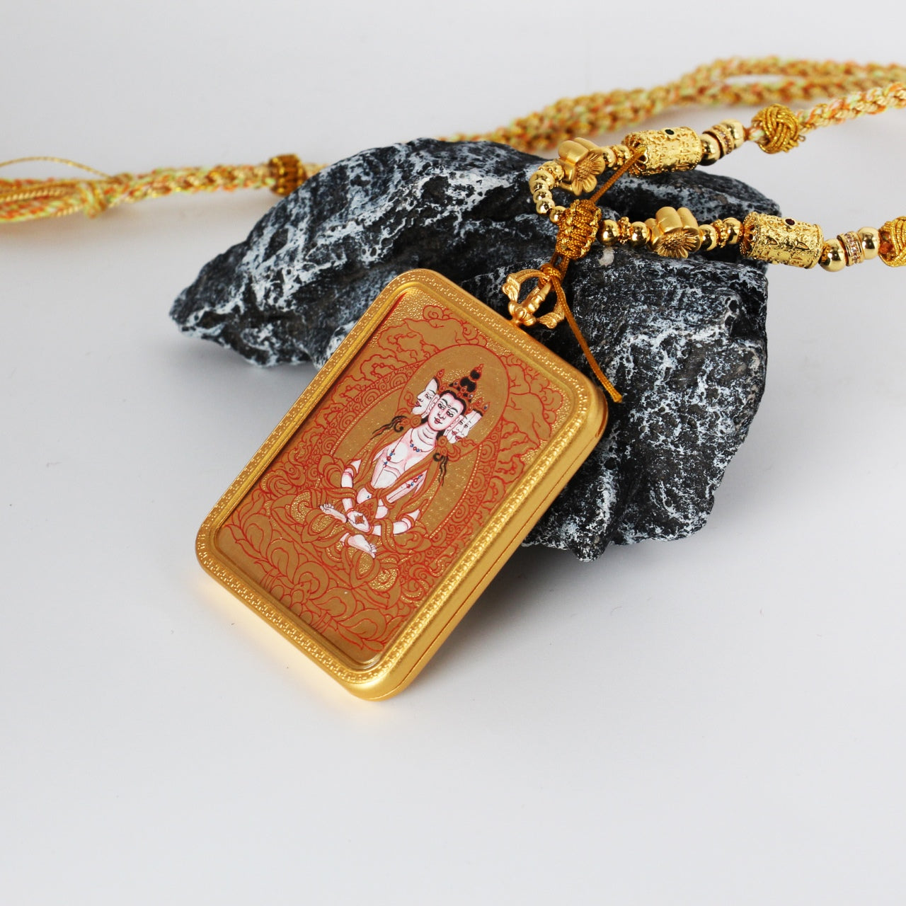 Complete view of the Vairocana Buddha mini thangka pendant paired with a braided cord and decorative metal beads, presented as a portable Tibetan thangka artwork.