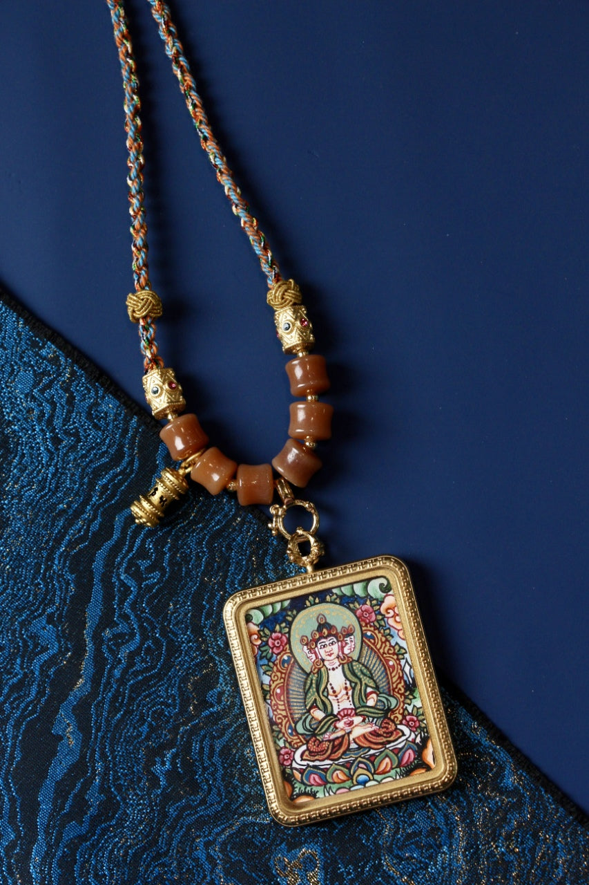 Detail view of a hand-painted Vairocana Buddha thangka pendant from Nepal, highlighting mineral pigment painting, bead accents, and traditional Buddhist art style