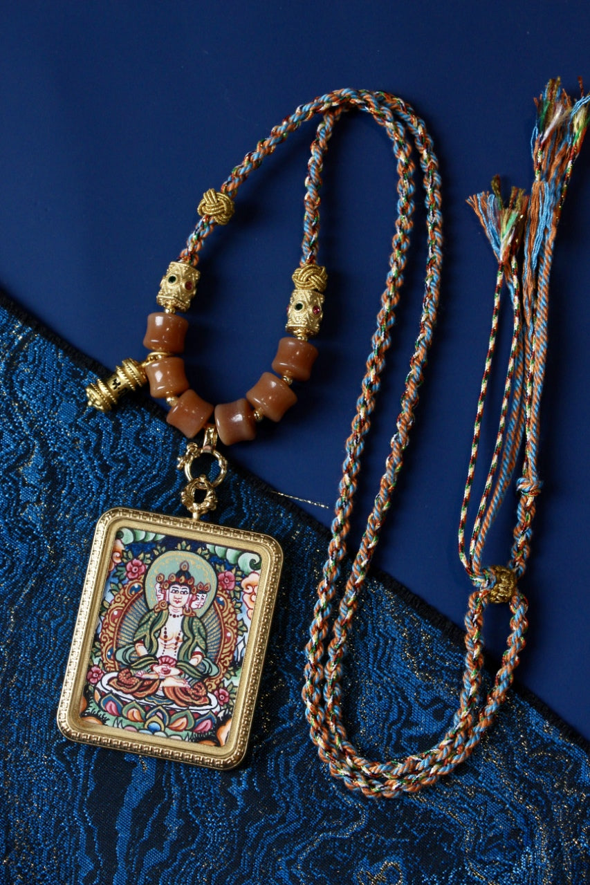Nepalese handcrafted Vairocana Buddha thangka pendant necklace with braided cord, showcasing traditional Buddhist painting and pendant craftsmanship