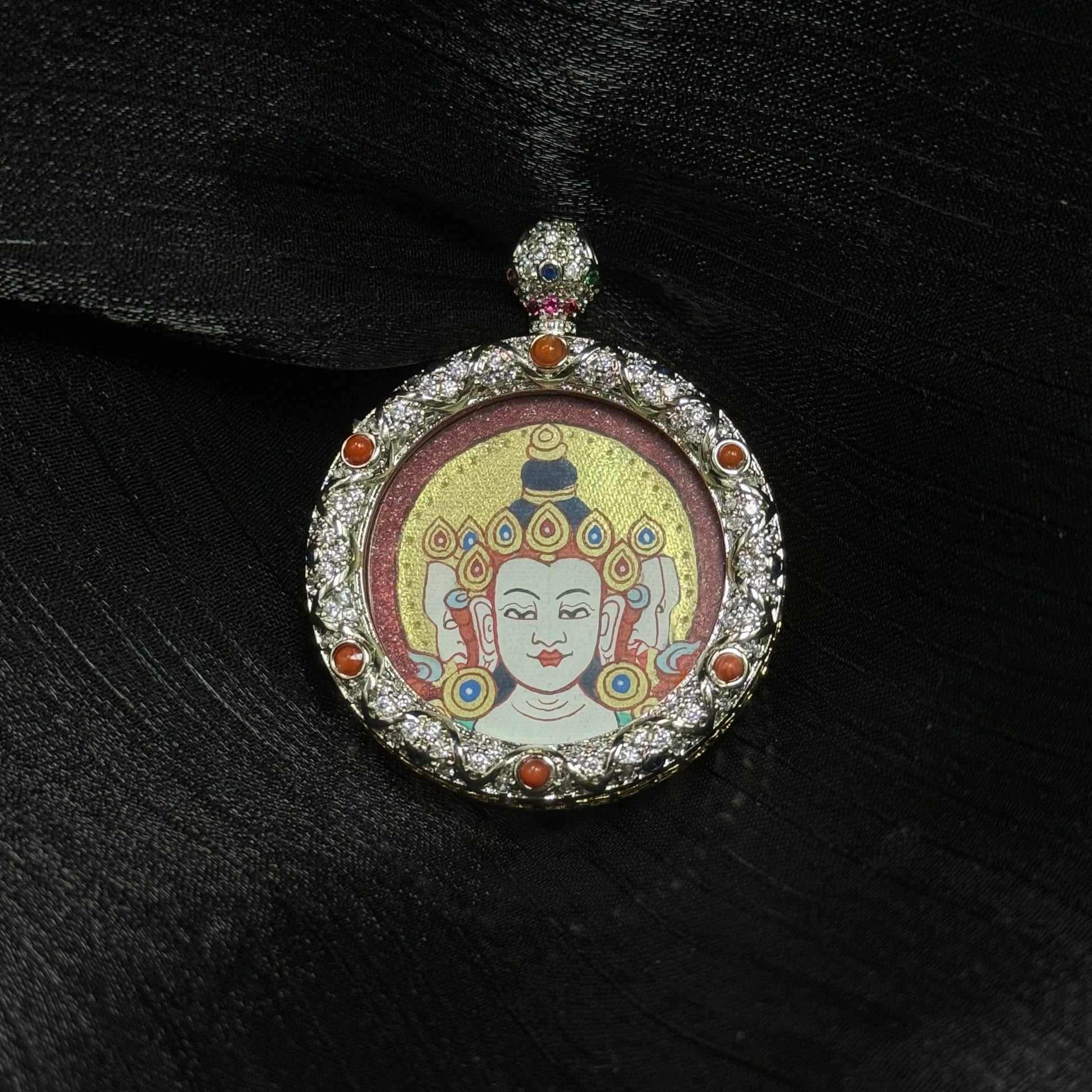 Vairocana Buddha miniature thangka pendant featuring hand-painted Buddha head with gold halo, cinnabar mineral background, and jeweled copper pendant frame