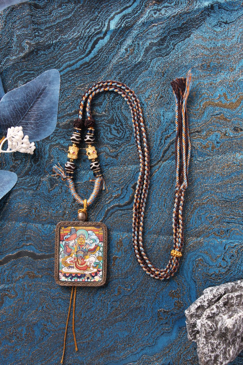 Full set display of Vaishravana wealth deity thangka pendant showing the braided necklace, decorative beads and metal spacers, and the sterling silver case framing the hand-painted 3.5 × 4.5 cm thangka artwork