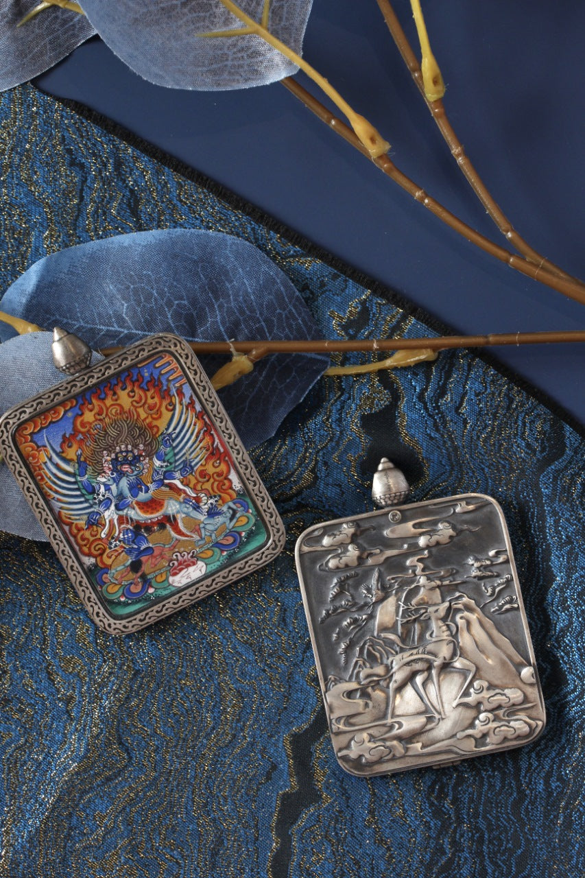 Front and back display of a Vajrakilaya mini thangka pendant, showing the hand-painted thangka image on the front and an engraved pure silver back plate inspired by Dunhuang art motifs.