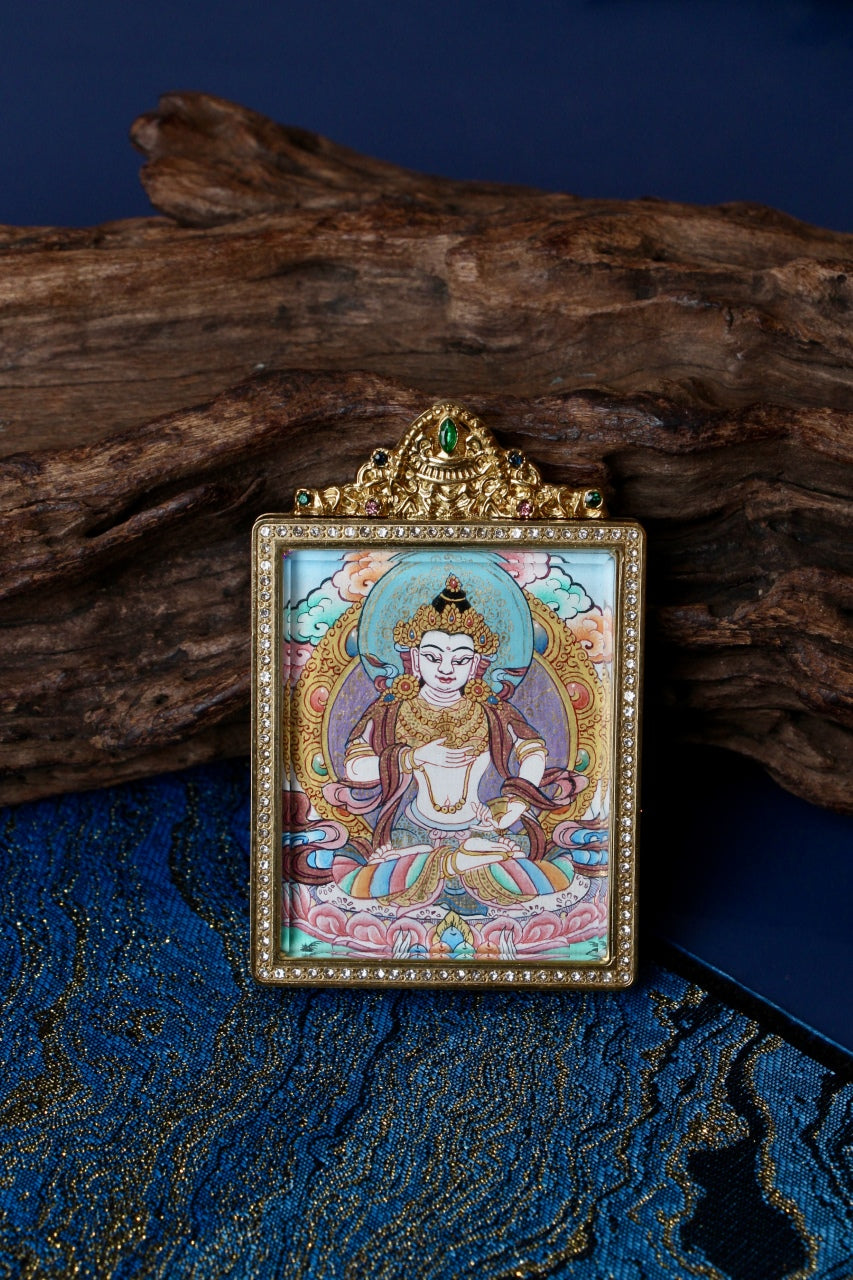 Front view of Vajrasattva mini thangka pendant centered on wood background, showing hand-painted thangka art and jeweled titanium steel frame, Nepal series