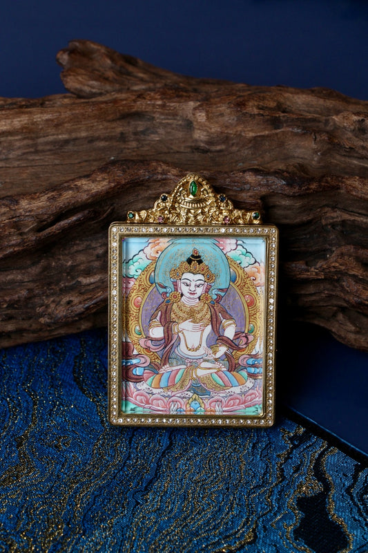 Front view of Vajrasattva mini thangka pendant centered on wood background, showing hand-painted thangka art and jeweled titanium steel frame, Nepal series