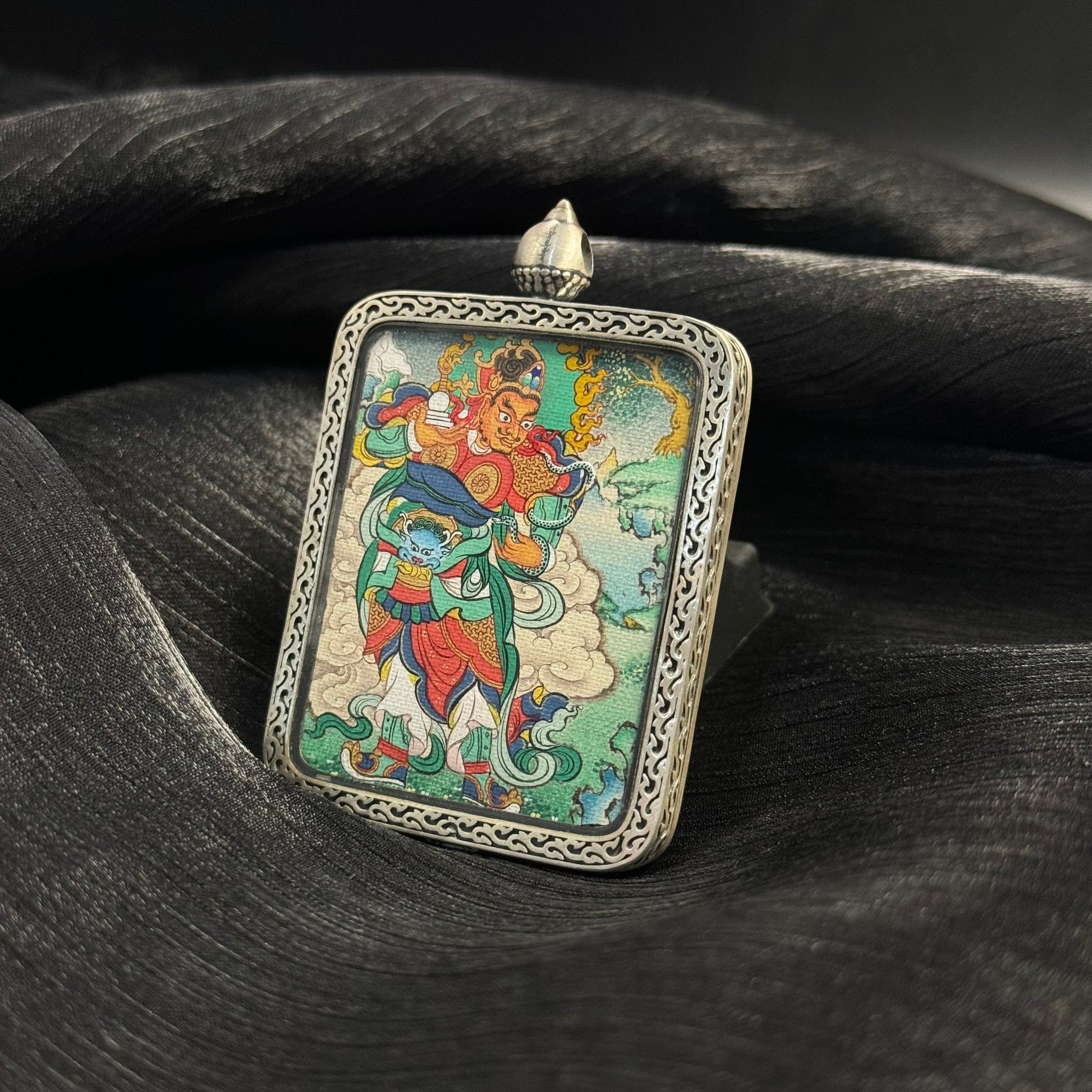 Virupaksha Western Guardian King mini thangka pendant displayed on dark fabric background highlighting Tibetan hand-painted protector deity artwork