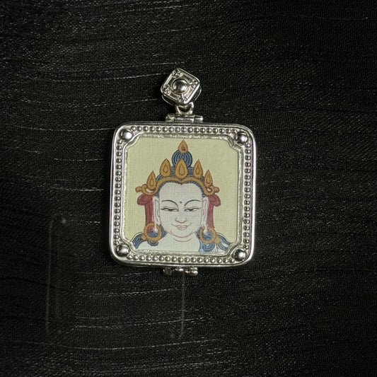 Close-up of a square mini thangka pendant featuring a single-sided hand-painted white face with a gold crown and blue hair details, set in a silver-tone frame with beaded border, rounded corner beads, and a square top bail on black background