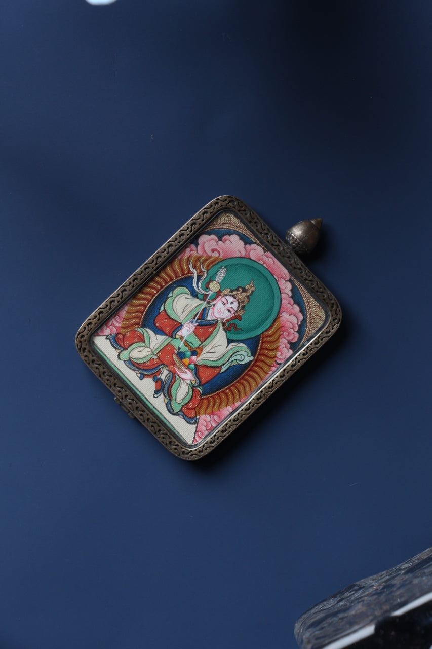 Angled product view of the White Lhamo mini thangka pendant from the Tibetan Red Cloud Zangka Series, hand-painted with mineral pigments and set in a sterling silver protective case for daily wear or shrine use.