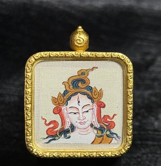 Close-up view of a White Tara mini thangka pendant featuring a hand-painted Tibetan deity portrait on canvas, set within a square gold-toned frame with detailed ornamental border.