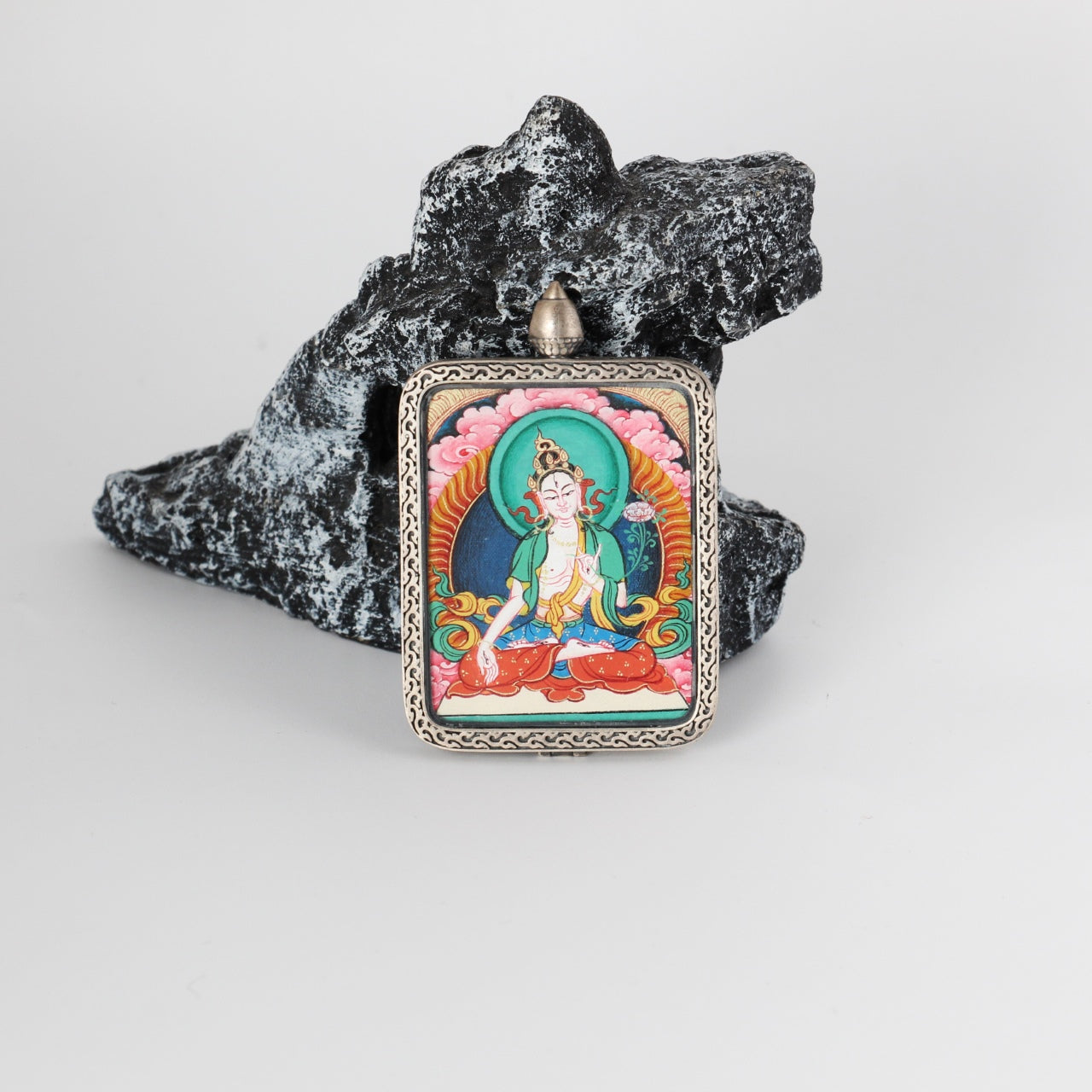 Front view of White Tara mini Thangka pendant, hand-painted with mineral pigments, set in a pure silver case with traditional Tibetan decorative patterns.