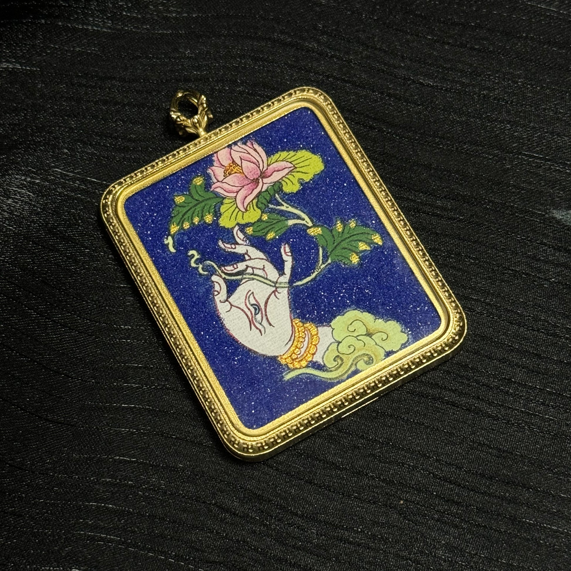 Angled display of a White Tara sacred hand thangka pendant featuring lotus flower symbolism and traditional gold frame miniature thangka craftsmanship.