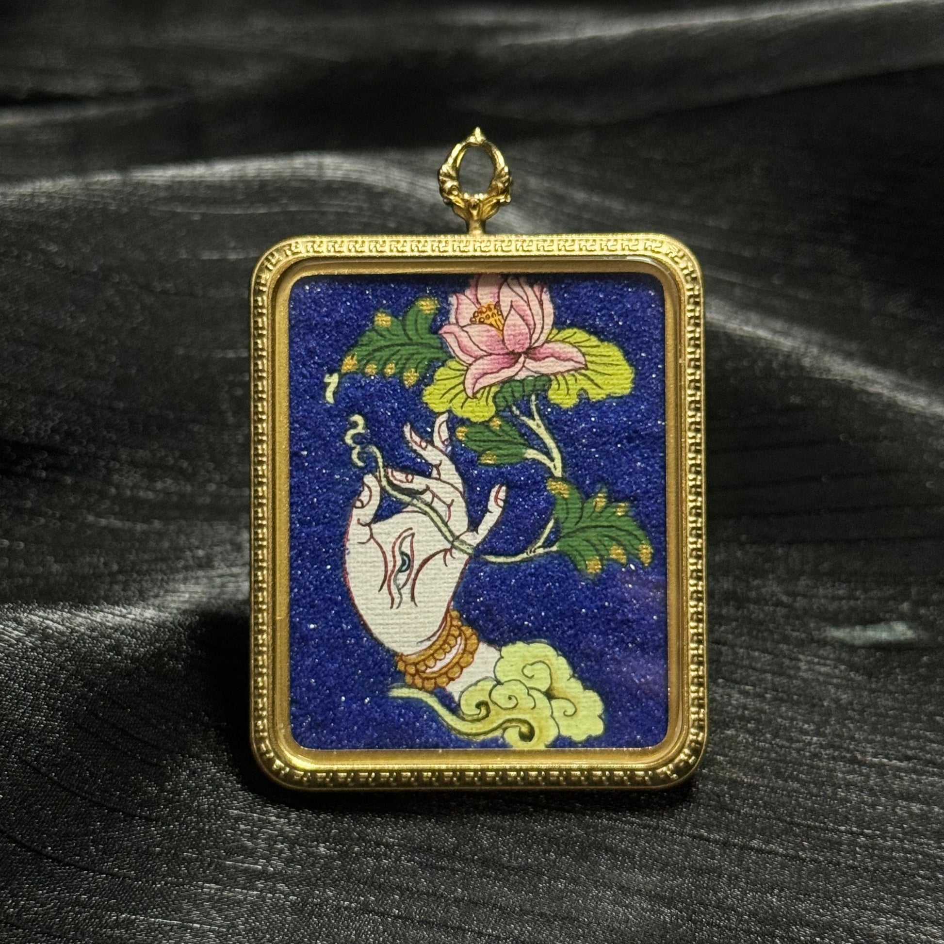 Hand-painted White Tara sacred hand mini thangka pendant showing a graceful Tara hand holding a lotus flower against a deep blue background in a gold pendant frame.