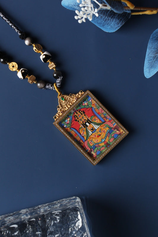 Angled view of Wu Ye Dragon God thangka pendant necklace, depicting the Fifth Dragon Prince seated in royal posture, symbolizing wealth guardianship and good fortune