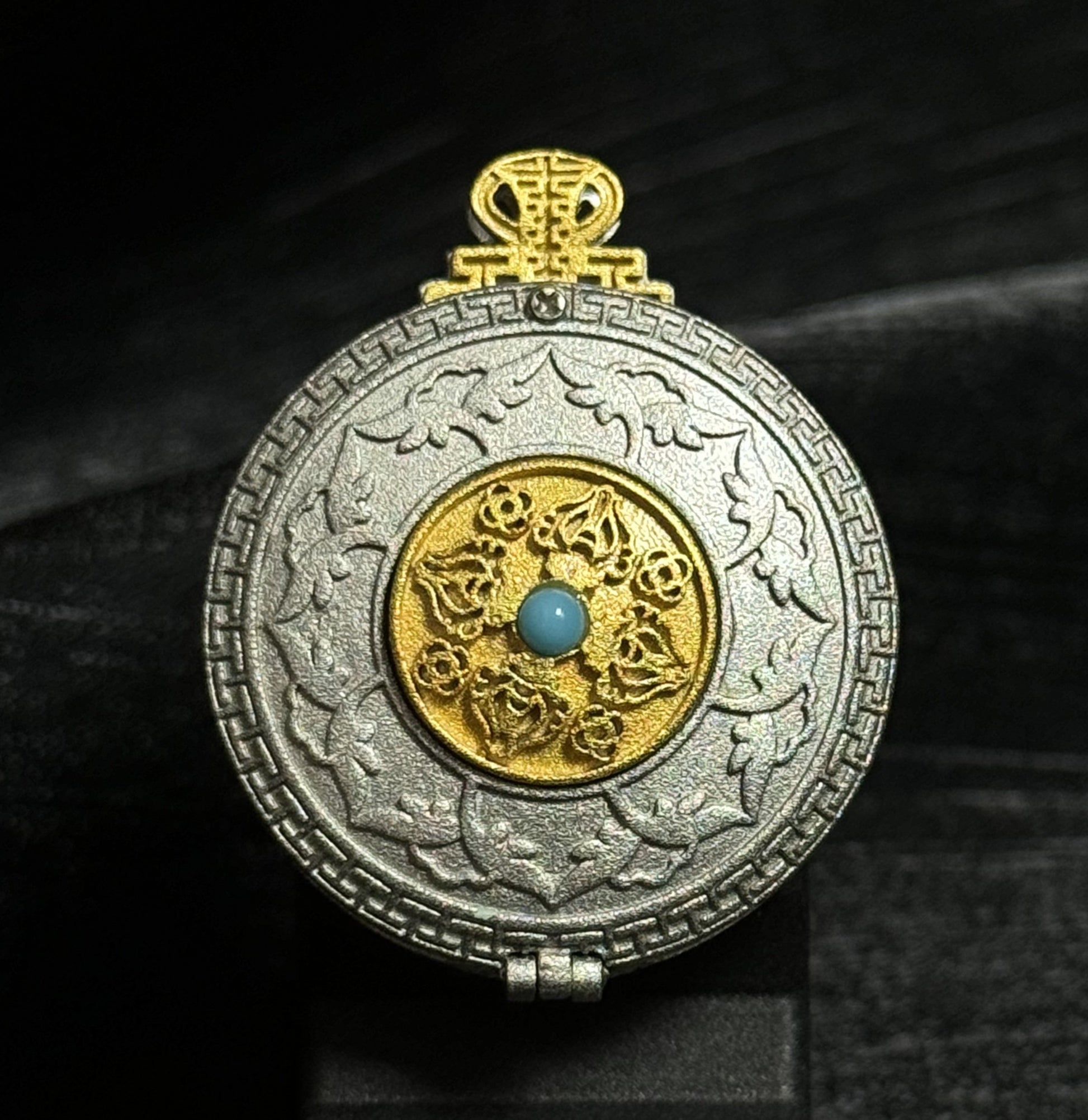 Front view of a Yamantaka Mandala mini thangka pendant with hand-painted mandala artwork inside a circular gold-toned and silver-toned pendant frame.
