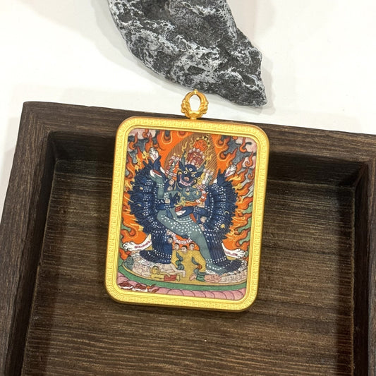Angled view of Yamantaka thangka pendant, highlighting the copper frame texture, hand-painted surface, and layered mineral pigment colors.