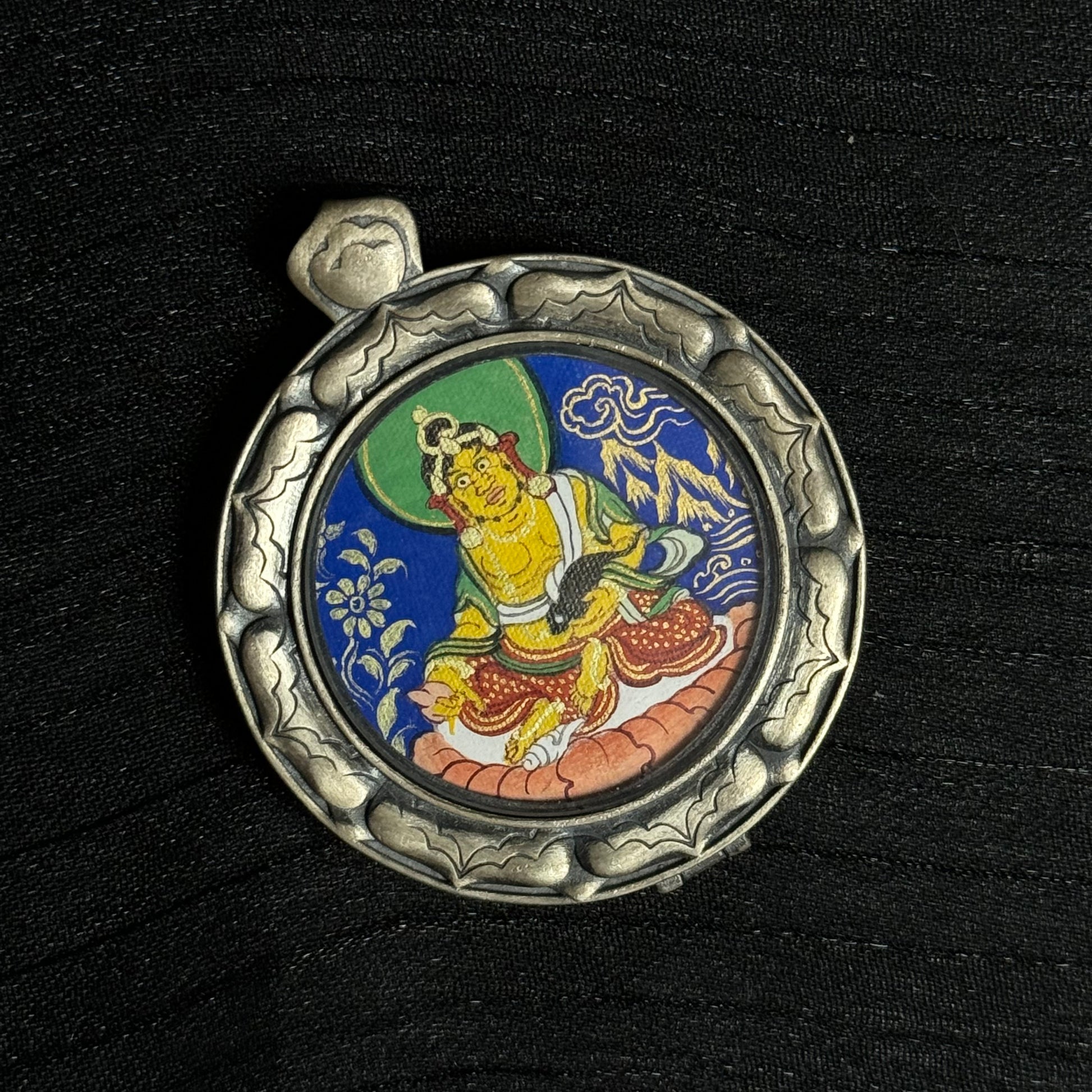 Close-up view of the circular Yellow Jambhala thangka painting showing detailed deity figure, lotus seat, and vibrant mineral pigment colors in Rebgong style.