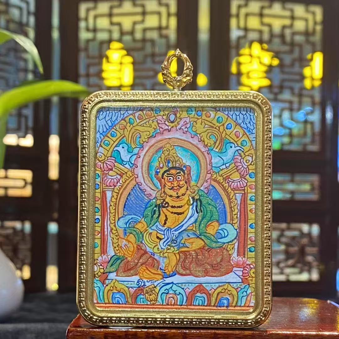 Front view of hand-painted Yellow Jambhala Thangka set in a titanium steel Tibetan Gawu pendant, wealth and protection amulet