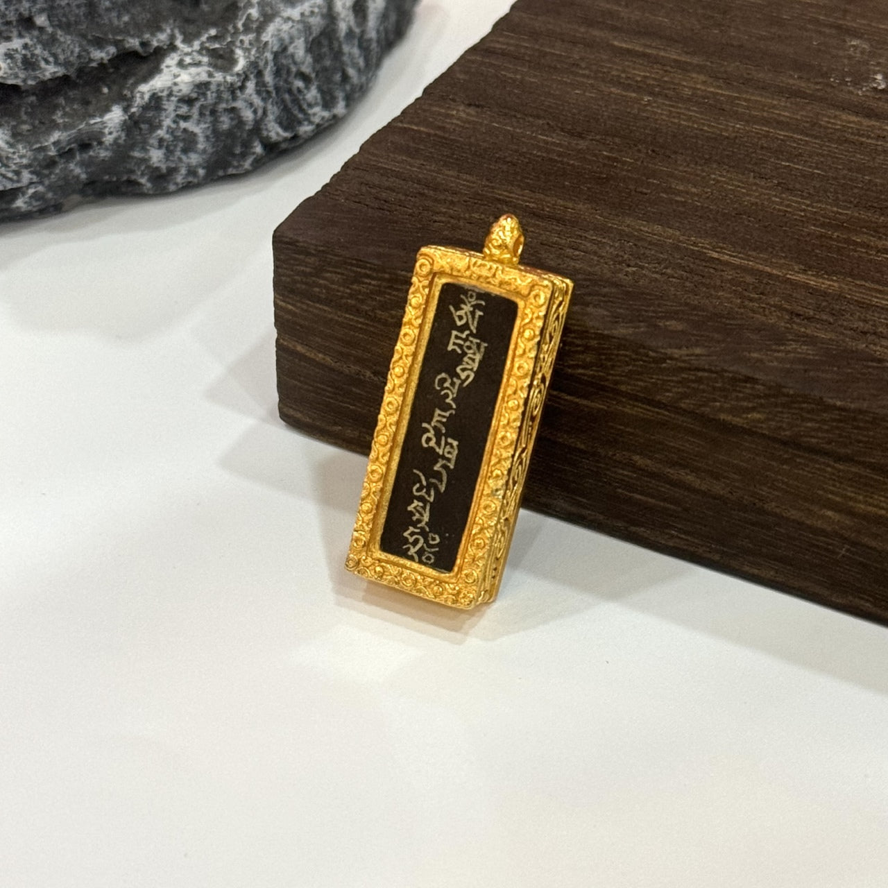Side perspective of the Yellow Jambhala mantra mini pendant, showing its slim rectangular format and the textured gold-toned copper casing around the mantra panel.