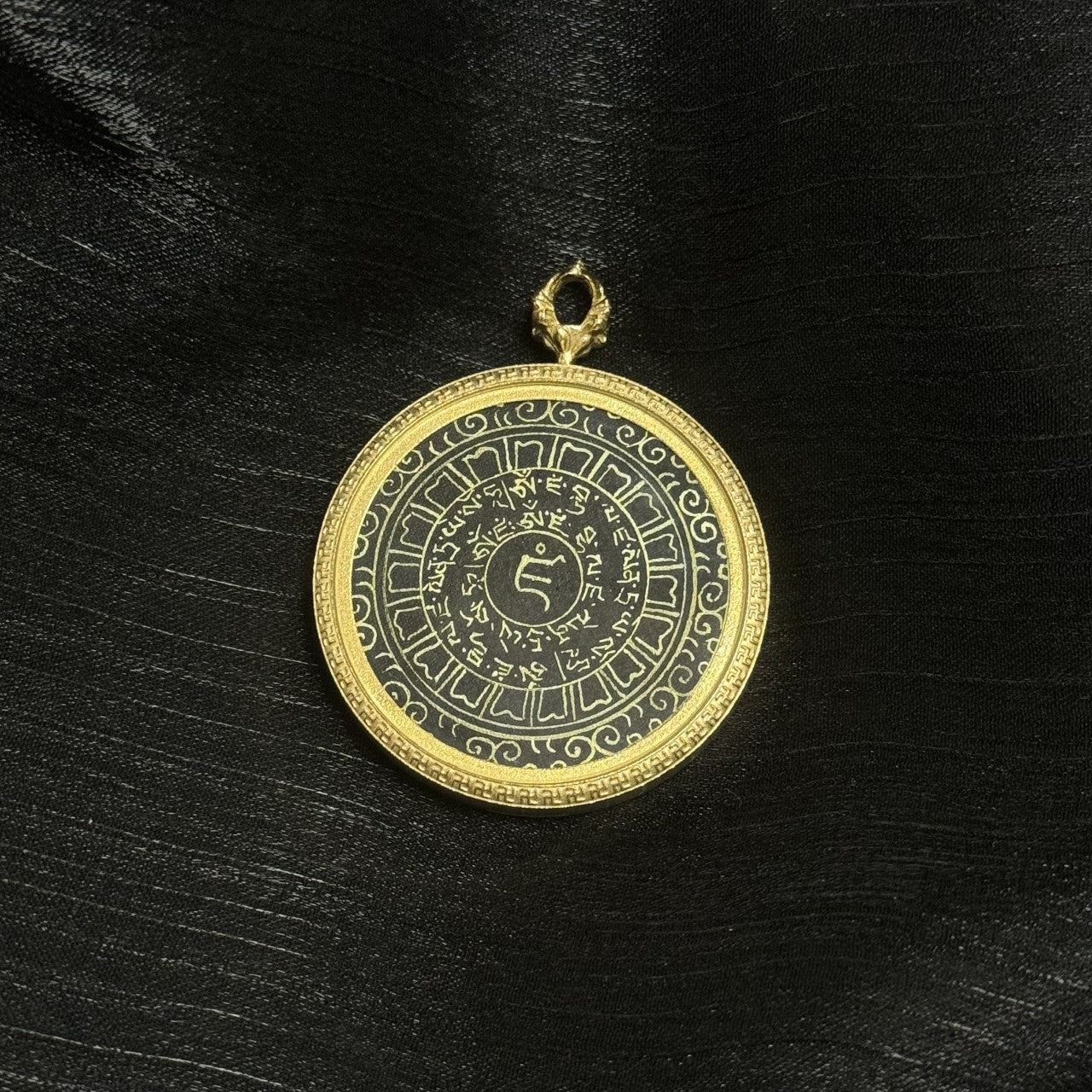 Detail view highlighting the central seed syllable and fine hand-written gold powder script of the Yellow Jambhala heart mantra within the circular design.