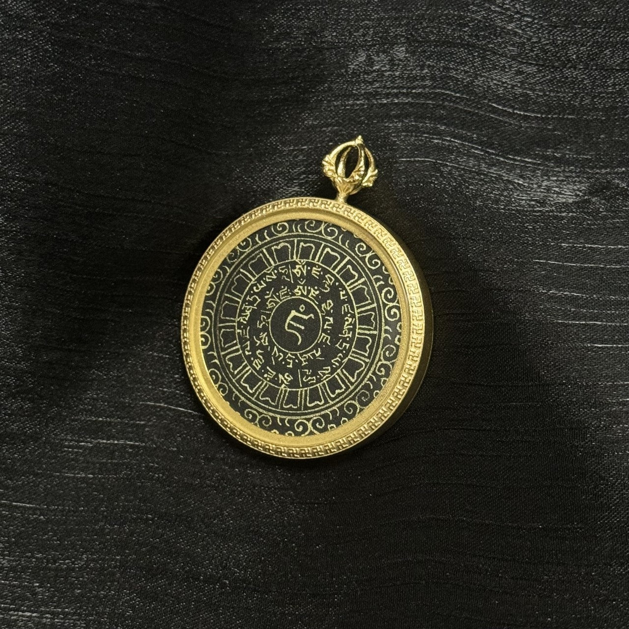 Full view of the Yellow Jambhala heart mantra pendant featuring concentric rings of Tibetan characters, central seed syllable, and a gold-tone frame with a decorative border.