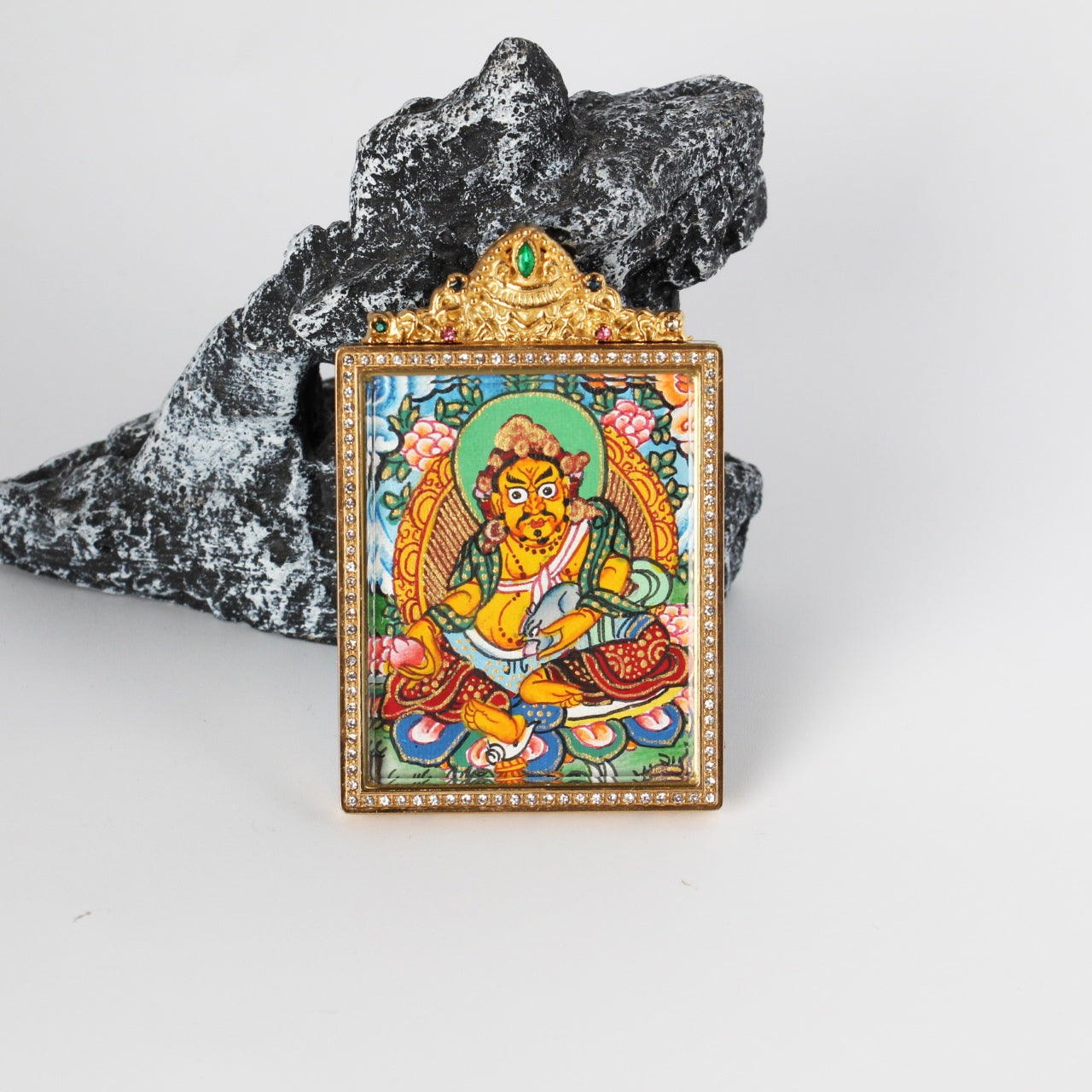 Angled view of Yellow Jambhala mini thangka pendant, hand-painted with mineral pigments, set in a gold-tone titanium steel case with crystal-style border and ornate top detail