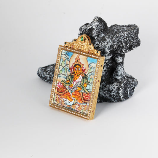 Angled view of Yellow Jambhala mini thangka pendant showing airy cloud background composition, hand-painted mineral pigments, and gold-tone titanium steel case with crystal-style border