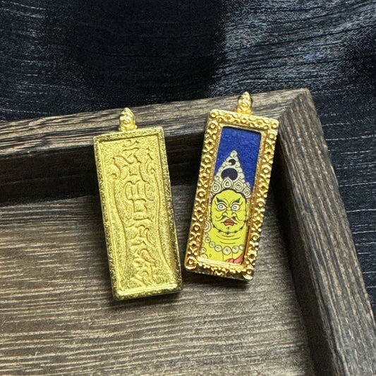 Front and back view of a Yellow Jambhala mini thangka pendant, showing the hand-painted yellow deity face on a deep blue background with crown details, and the back of the copper case with embossed script and textured surface.