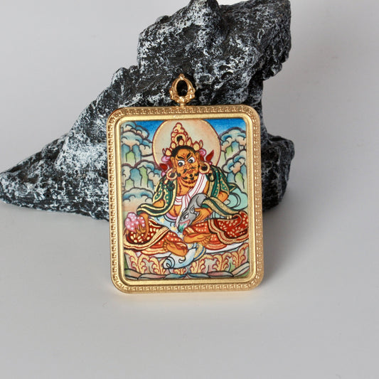 Front view of Yellow Jambhala mini thangka pendant showing hand-painted deity portrait with halo, cloud background, and detailed robes inside a rectangular gold-tone titanium steel frame.