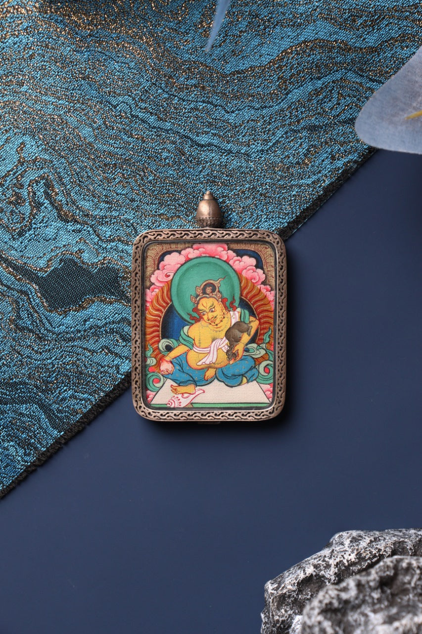 Front view of the Yellow Jambhala mini thangka pendant in Zangka format, a compact Tibetan devotional artwork hand-painted with mineral pigments and protected by a sterling silver case, suitable for travel devotion and personal shrine display.