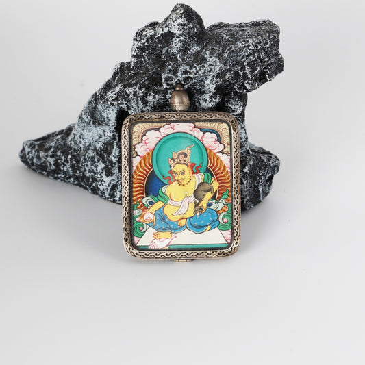 Front view of Yellow Jambhala mini thangka pendant from the Red Cloud Series, hand-painted with mineral pigments and set in a rectangular Dunhuang Nine-Colored Deer sterling silver case