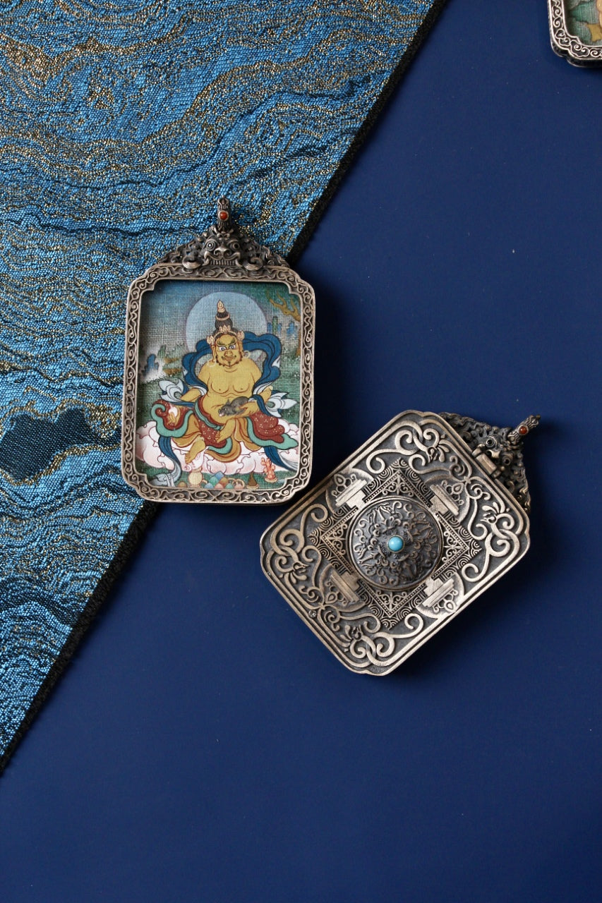 Yellow Jambhala mini thangka pendant photographed with the carved vintage silver gawu back visible; hand-painted mineral pigments on a 3.5 × 4.5 cm painting—chosen by collectors and practitioners for wealth-themed symbolism and grounded stability (often aligned with Capricorn/Taurus meanings).