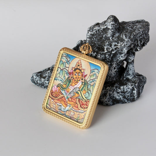 Side-angled view of Yellow Jambhala mini thangka pendant showing the rectangular gold-tone case thickness, frame edge details, and the painted surface with fine linework.