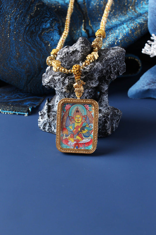 Yellow Jambhala mini thangka pendant photographed upright, highlighting rectangular double-sided titanium steel case and balanced Rebgong composition