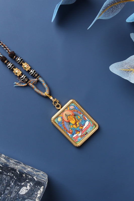 Yellow Jambhala mini thangka pendant featuring the Wealth Deity Dzambhala, hand-painted with mineral pigments in Rebgong style, set in a titanium steel frame with braided cord necklace.