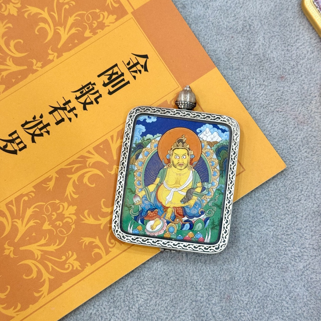 Flat lay of Yellow Jambhala pendant showing the silver case border, top bail, and fine painting details including the halo, offerings, and lotus base.