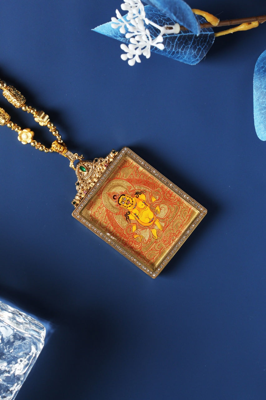 Angled view of the Yellow Jambhala Rebgong gold thangka pendant showing the raised metal frame, layered gold background, and refined edge craftsmanship.