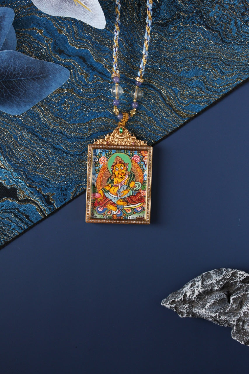 Nepalese Yellow Jambhala thangka pendant in gold titanium steel frame, square format with detailed Buddhist wealth deity painting
