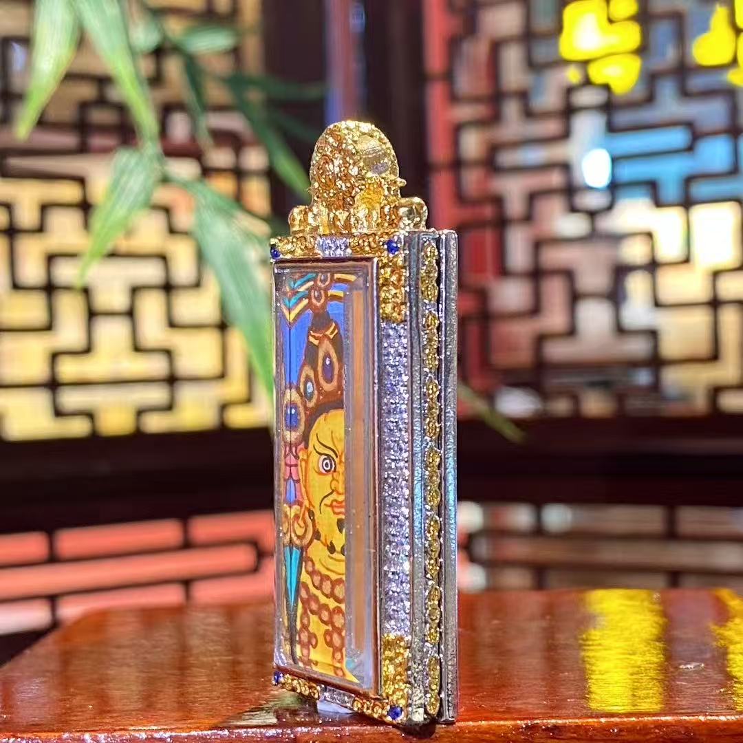 Side view of a vertical Yellow Jambhala hand-painted mini Thangka pendant showing the traditional copper Gau box thickness and structure