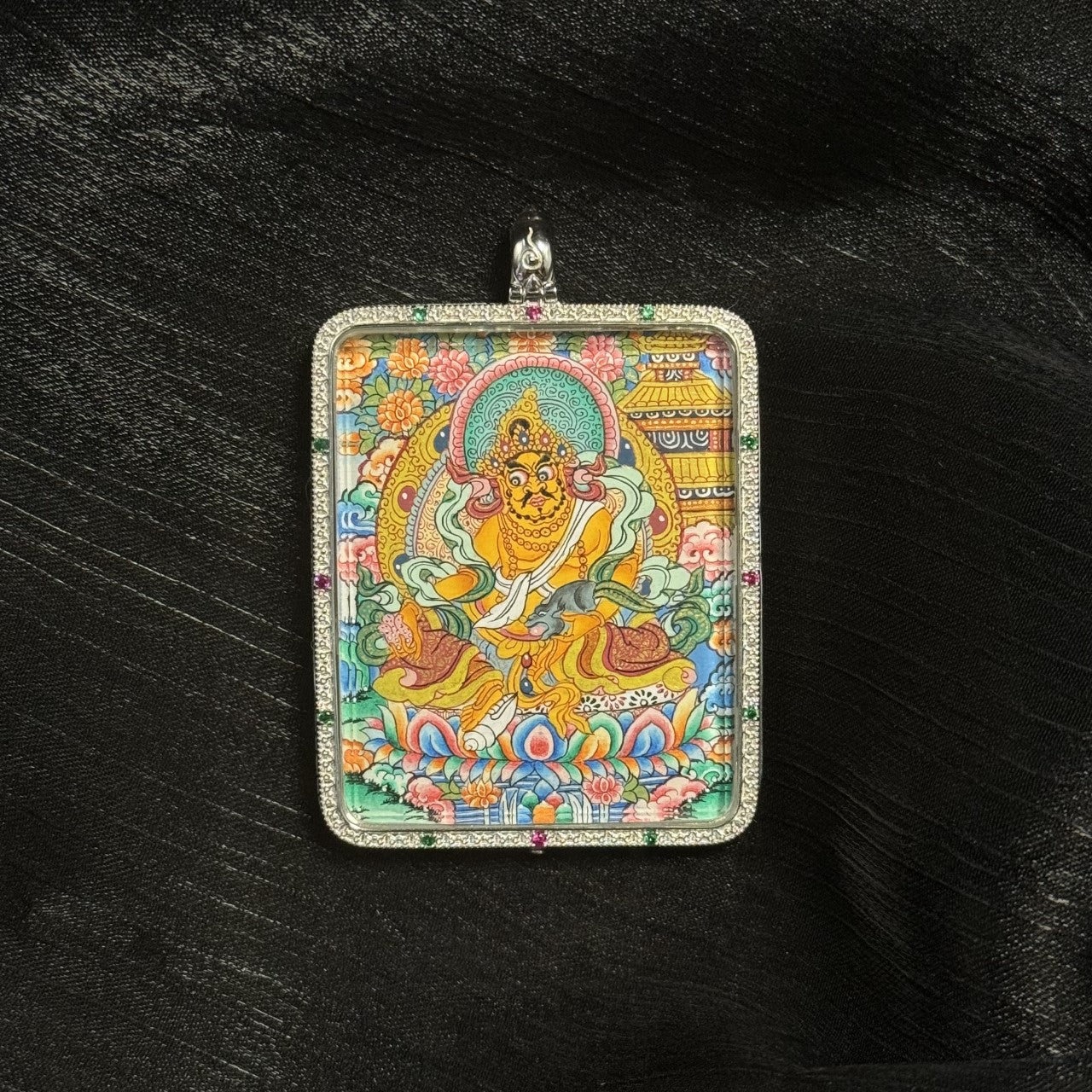 Hand-painted Tibetan Yellow Jambhala miniature thangka pendant featuring the wealth deity holding a mongoose and seated on a lotus base with vibrant mineral pigment colors.