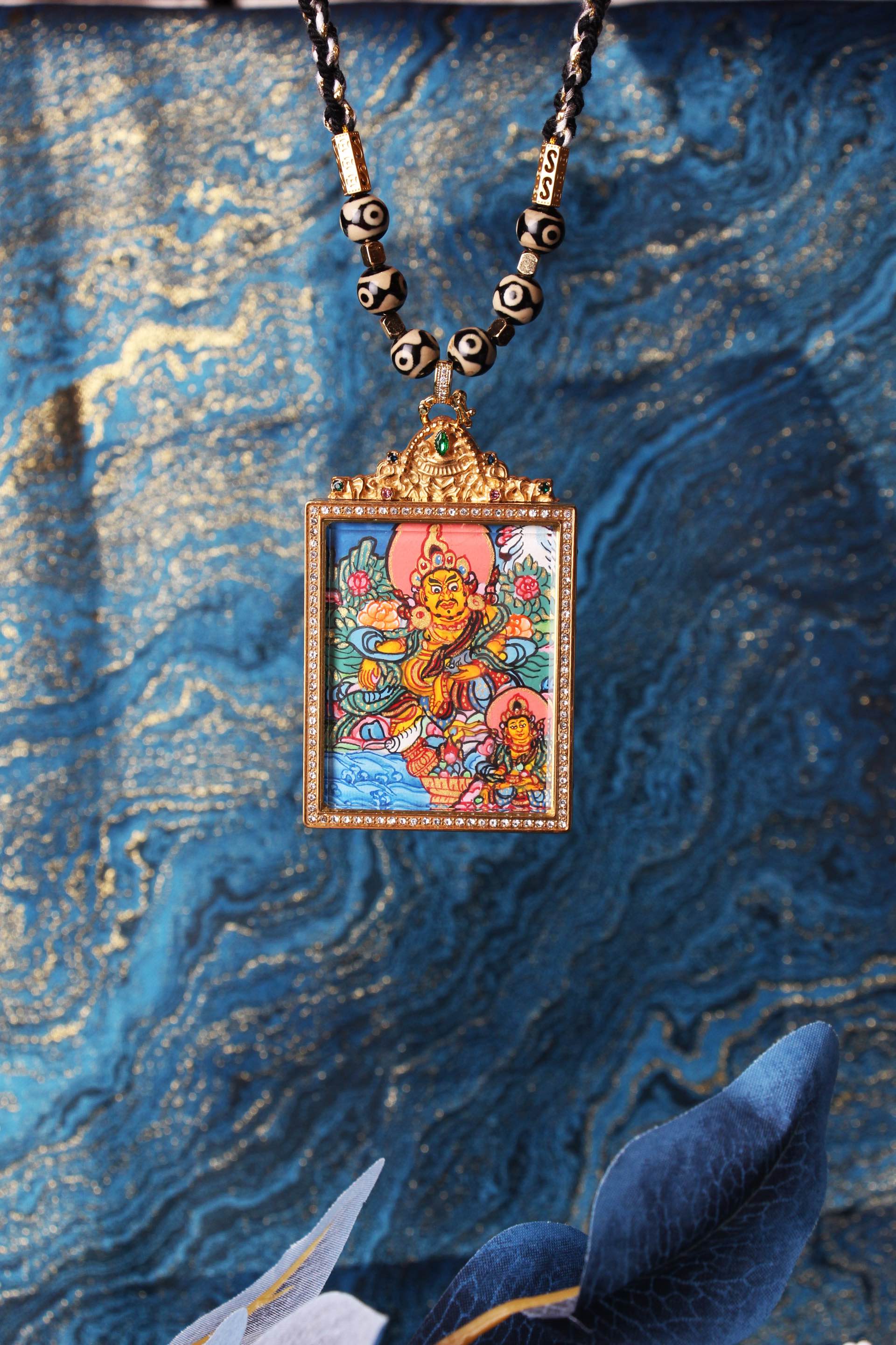 Dual-deity thangka pendant displayed as a wearable necklace, showing the square jewelry-style case with crystal border, ornate top crown, and the colorful hand-painted thangka image.