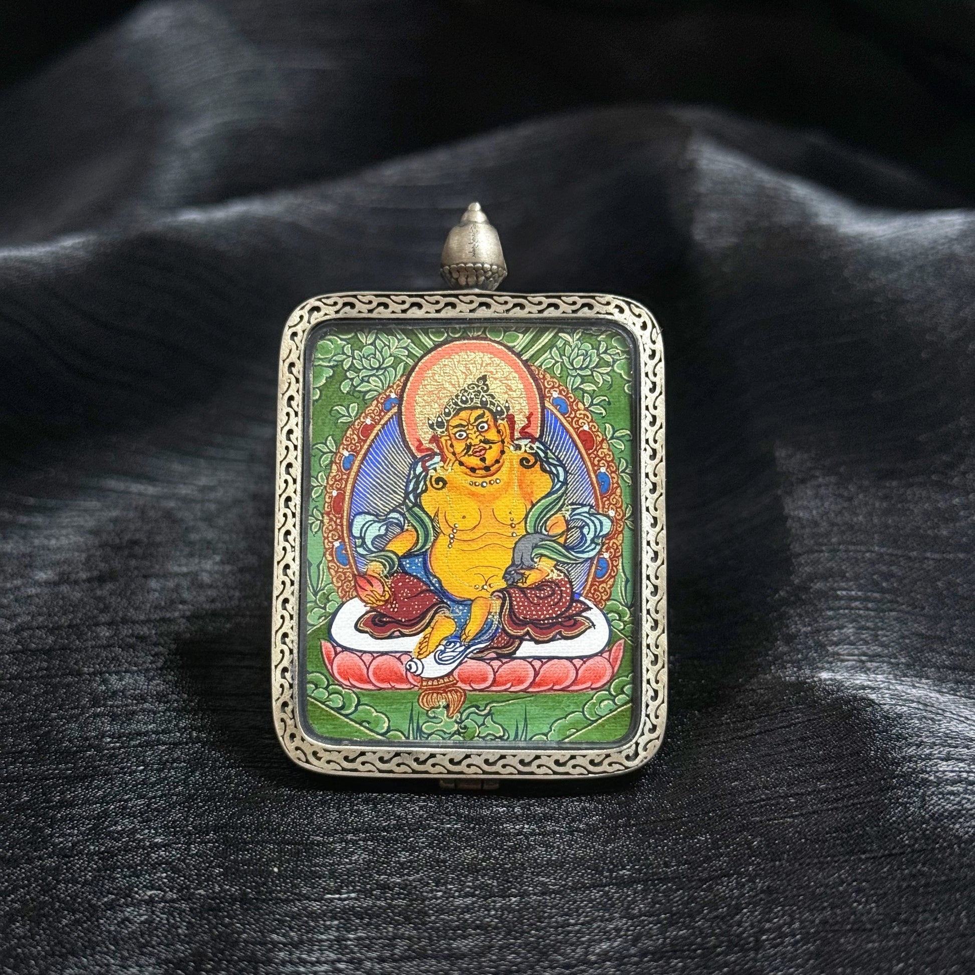 Close-up of Yellow Jambhala Tibetan wealth deity mini thangka pendant featuring lotus seat, halo background, and fine Rebgong mineral pigment painting details