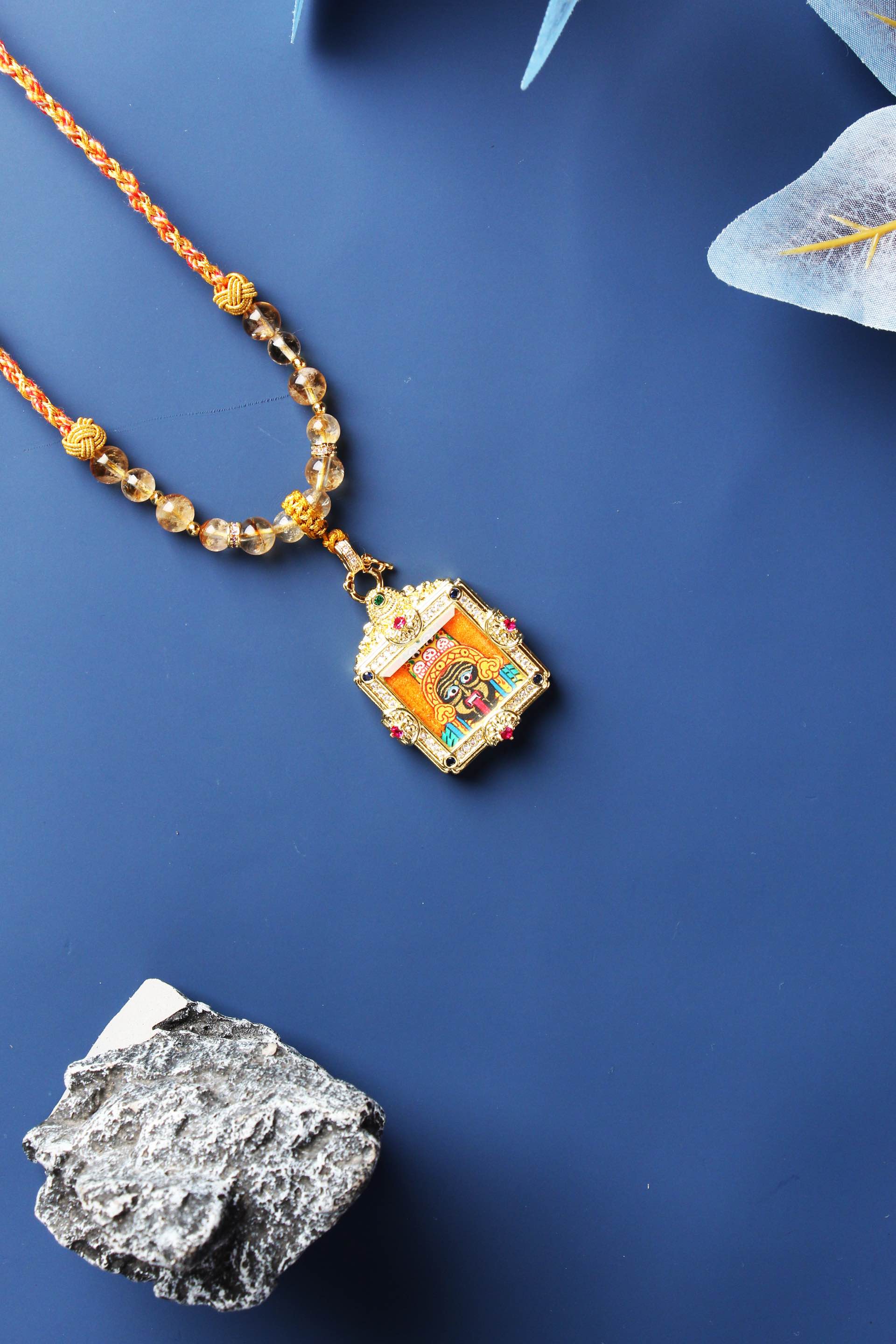 Full flat-lay of a beaded necklace featuring a Zaki Lham mini thangka pendant in a gold-tone square frame