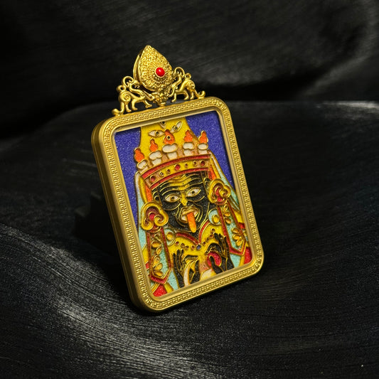 Angled view of handcrafted Zaki Lhamo cloisonné enamel pendant highlighting gold-plated copper casing, raised enamel details, and colorful Tibetan deity design.