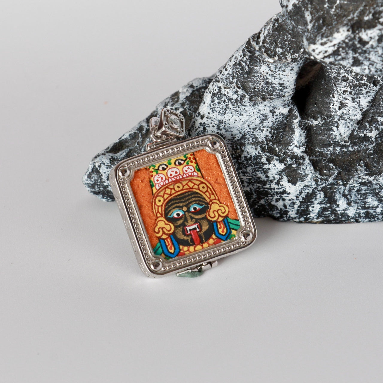 Angled view of Zaki Lhamo mini thangka pendant highlighting the silver-plated square frame, beaded border, corner rivets, and pendant bail hardware.