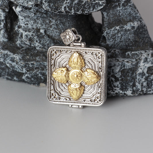 Back view of Zaki Lhamo mini thangka pendant showing gold vajra cross relief on square silver-plated case with decorative borders.