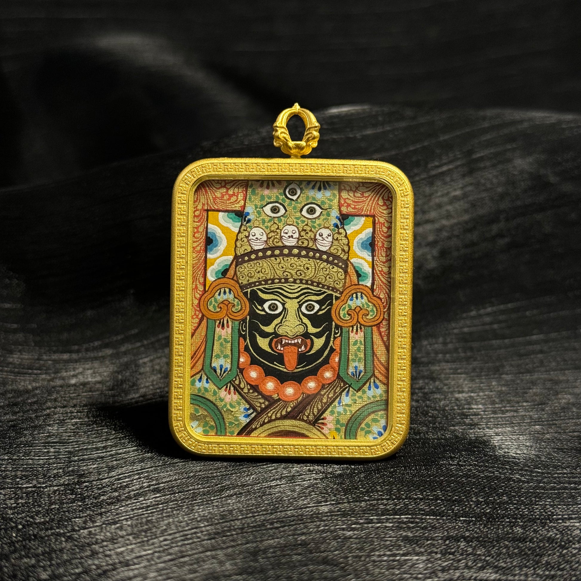 Front view of Zaki Lhamo mini thangka pendant featuring a hand-painted Rebgong thangka portrait with mineral pigments, gold powder detailing, and a textured gold frame setting.